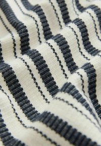 Tissu tissé avec un fond crème et présentant des rayures verticales bleu marine. La texture est cannelée, avec des largeurs et des espacements variés dans le motif.
