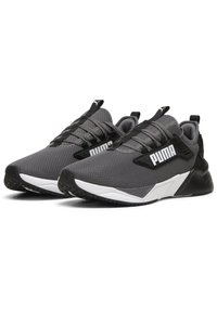 Zapatillas deportivas grises con parte superior de malla, acentos negros, suela intermedia gruesa blanca y suela exterior de goma texturizada con un patrón de relieve pronunciado.
