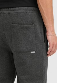 Grå joggebukser med en stor baklomme og en liten merkeetikett. Laget av mykt stoff med elastisk linning for komfort.
