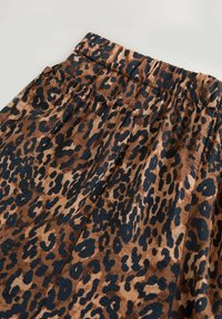 Jupe imprimée léopard en brun et noir. Tissu doux avec une taille élastique et des détails de plis qui améliorent le design global.