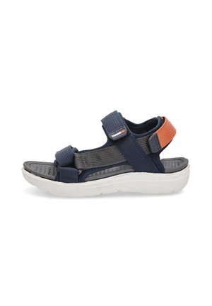 Sandalias azul marino con tiras de textil, cierres de Velcro ajustables y una gruesa suela de goma blanca con una plantilla texturizada gris.