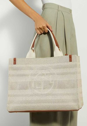 Sac fourre-tout tissé beige avec des rayures horizontales, des accents marron et deux poignées. Surface texturée et détail de marque à l'avant.