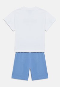 Λευκό βαμβακερό T-shirt με κοντά μανίκια σε συνδυασμό με μπλε βαμβακερά σορτς. Και τα δύο ρούχα έχουν απαλή, λεία υφή και απλό σχέδιο.