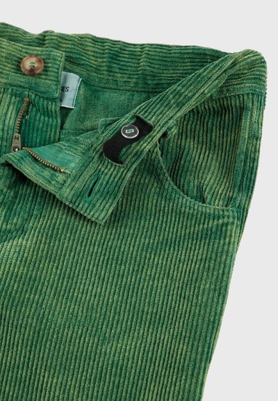 Pantalones de pana verdes con cinturilla ajustable con botones, cremallera y un borde de bolsillo frontal visible.