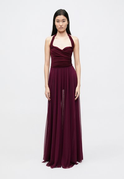 Burgundy evening gown with a fitted bodice, halter neckline, pleated details, and a flowing, sheer skirt with a front slit.