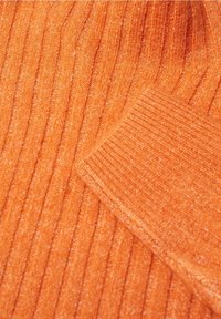 Tissu en maille orange côtelé avec des textures variées. Matière douce et épaisse ; présente un éclat subtil et un motif uniforme partout.