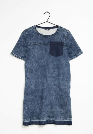 Sukienka z denimu z krótkim rękawem, okrągłym dekoltem i ciemną kieszenią na piersi z denimu, wisząca na czarnym metalowym wieszaku na białym tle.
