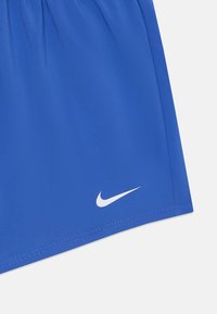 Pantaloni sportivi blu realizzati in tessuto liscio, con una cintura elastica e un piccolo logo Nike bianco vicino all'orlo.