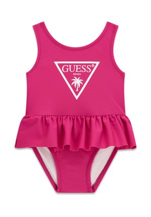 Bañador rosa brillante para niño pequeño con falda con volantes, diseño sin mangas y logo blanco "GUESS Beach" con palmera en la parte delantera.