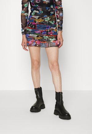 Farverig, mønstret minikjole med gennemsigtige lange ærmer, rynket tekstur og geometriske prints. Sorte chunky ankelstøvler med rundet tå.