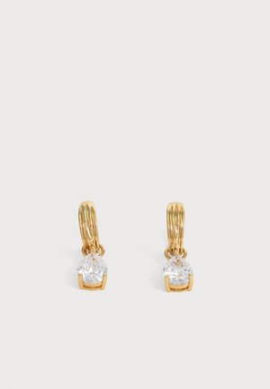 Boucles d'oreilles créoles en or, chacune avec une seule pierre précieuse claire en forme de poire suspendue à la base sur un fond clair uni.