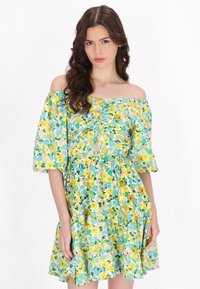Bloemendress met off-the-shoulder mouwen, een geplooide lijfje en een gelaagde rok in gele, groene en blauwe patronen. Zachte stoftextuur.