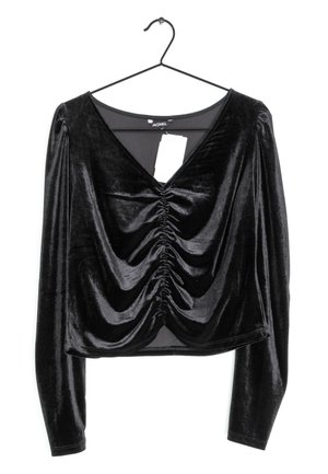 Sort fløjl langeærmet top med draperet front og V-halsudskæring, som har samlet tekstur og et mærke hængende i midten.