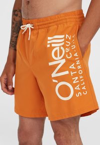 Bañador naranja con cintura elástica, cordón blanco y gran logo de O'Neill impreso en blanco en el lado izquierdo.