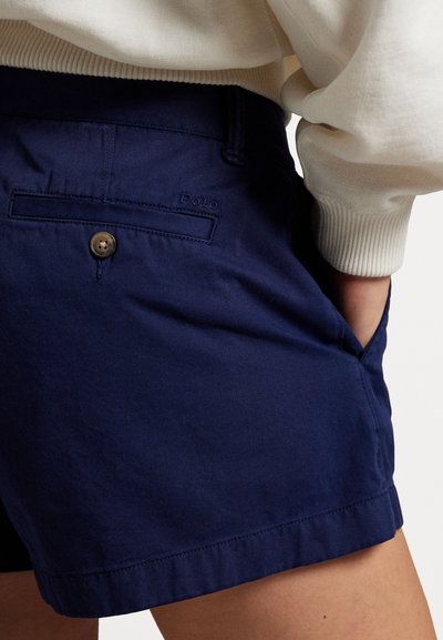 Marineblaue Baumwollshorts mit Knopfverschluss und seitlichen Taschen. Mit einem gestickten Polo-Logo auf der Gesäßtasche. Glatte Textur.