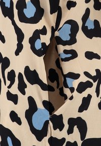 Tela de estampado de leopardo con manchas negras y azules claras sobre un fondo beige, con un detalle de abertura. Textura suave y diseño fluido.