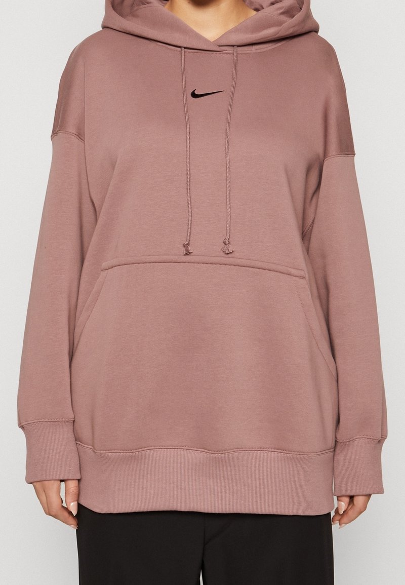 Übergroßer rosa Hoodie aus weichem Stoff mit einer Kängurutasche vorne und einem schwarzen Nike-Logo. Anpassbare Kordeln an der Kapuze.