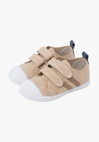 Beige kangaketsud ja valge kummist sõrmtipp, millel on kaks Velcro rihma ja tumblue aktsent kandadel.