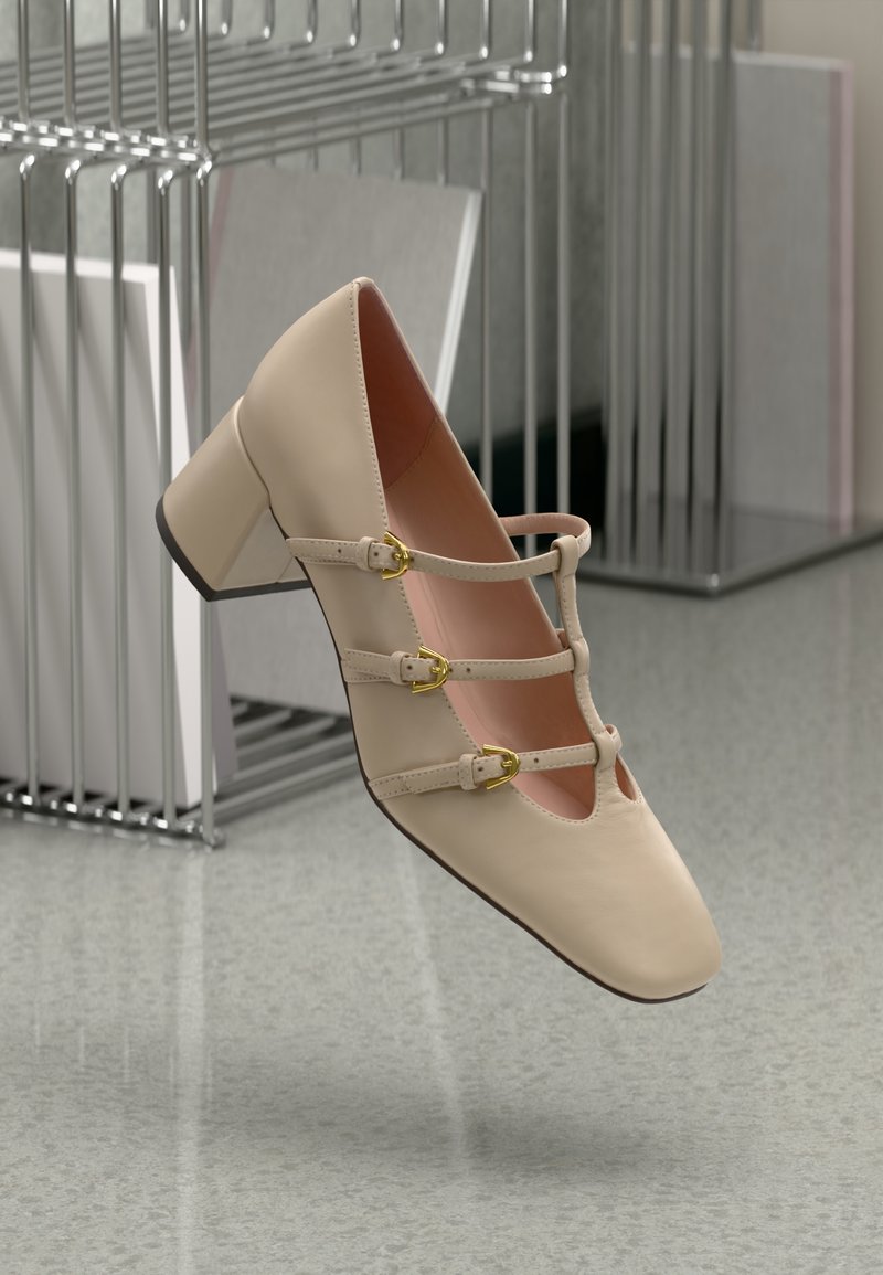 Beige leather block-heeled shoe with three adjustable straps and gold buckles. Square toe design, smooth texture, and pink inner lining.