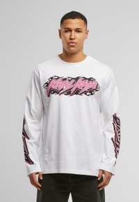 White long-sleeve T-shirt featuring pink and black graphic text on the front and down the sleeves. Fabric appears cotton with a smooth texture.