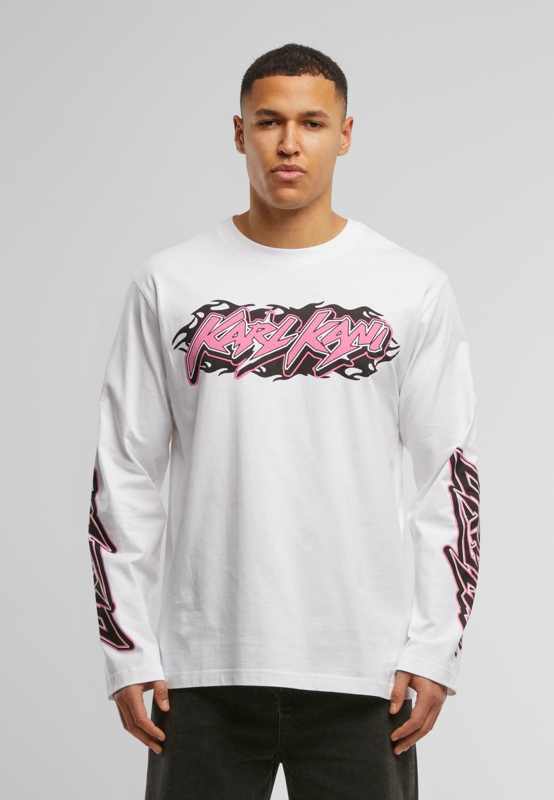 White long-sleeve T-shirt featuring pink and black graphic text on the front and down the sleeves. Fabric appears cotton with a smooth texture.