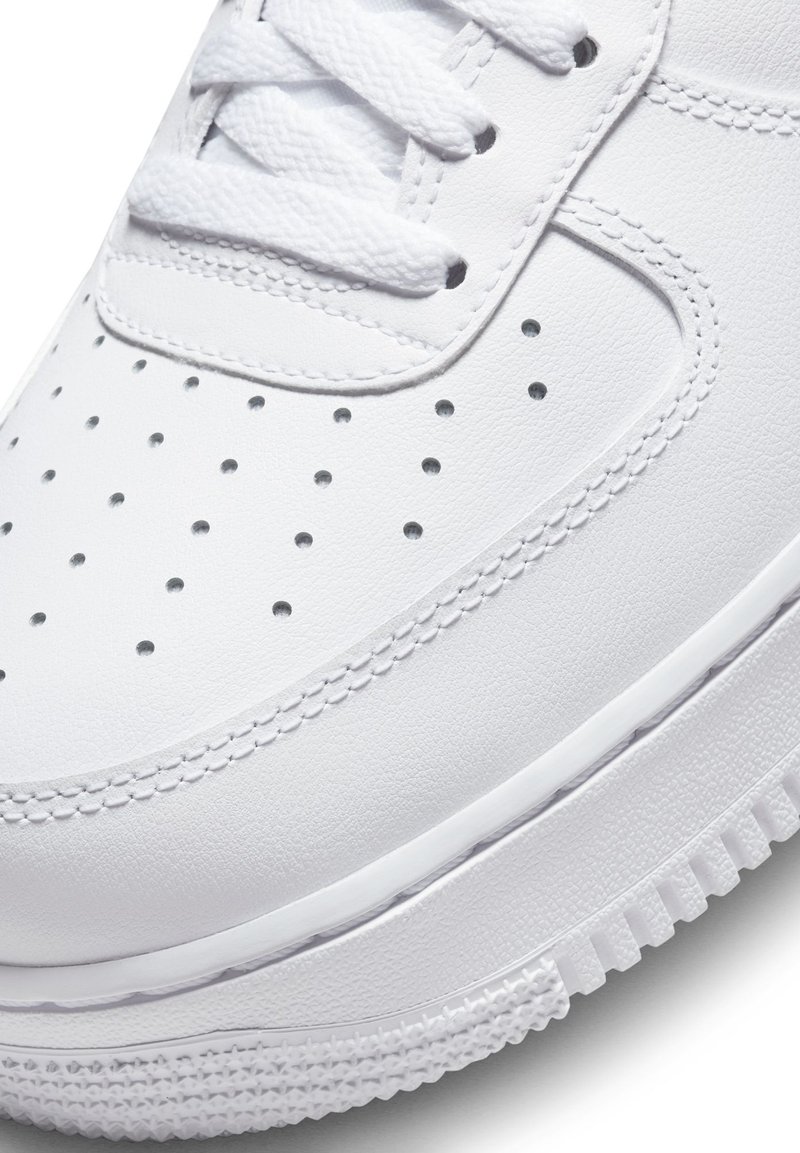 Białe skórzane sneakersy z perforowanym wzorem, płaskimi sznurówkami, teksturowaną powierzchnią i grubą gumową podeszwą z wzorowanym bieżnikiem.