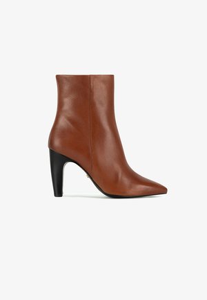 Brązowy skórzany botek za kostkę z noskiem w szpic i czarnym wysokim grubym obcasem, widoczny z boku na białym tle.