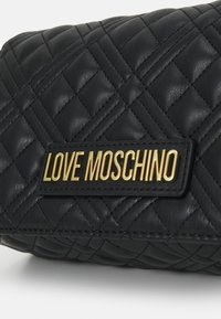 Pletená černá kožená kabelka s zlatým logem "LOVE MOSCHINO". Má obdélníkový tvar a texturovaný povrch s diamantovými vzory.