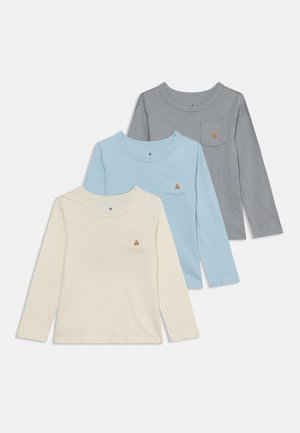 Trois tee-shirts à manches longues et à col rond, en crème, bleu clair et gris, chacun avec une poche poitrine et un petit ours brodé.