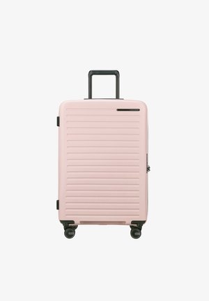 Valise rigide rose avec des rainures verticales, poignée noire rétractable et quatre roues pivotantes pour la mobilité. Fermeture zippée, design compact.