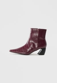Stivaletto bordeaux con texture di coccodrillo, punta appuntita e tacco a blocco nero curvo su sfondo bianco semplice.