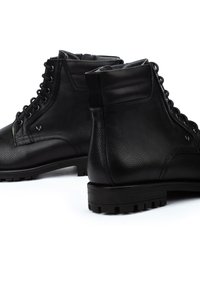 Botas de cuero negro con superficie texturizada, cordones en la parte delantera, soporte reforzado para el tobillo y suelas de goma resistentes para mayor tracción.