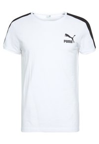 Bílý krátký rukáv tričko s černými akcenty na ramenou. Obsahuje černé logo Puma na levé straně hrudi. Vyrobeno z měkké bavlny.