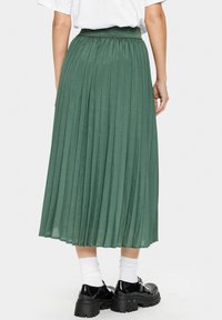 Gonna maxi plissettata di un profondo verde, realizzata in tessuto leggero con una vita elasticizzata. Presenta una trama fluida e un design a strati.