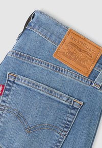 Ανοιχτό μπλε τζιν παντελόνι από denim με δερμάτινο ταμπελάκι με την ένδειξη "Levi Strauss & Co." στο πίσω μέρος, διαθέτει δύο πίσω τσέπες και αντίθετες ραφές.