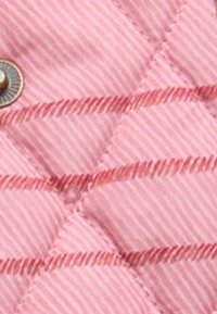 Tecido acolchoado rosa com riscas diagonais e costura proeminente. Inclui um detalhe de botão metálico redondo.