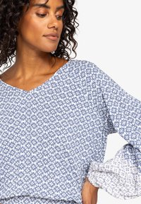 Blauwe en witte bloempatronen blouse met een V-hals en lange, licht gepofte mouwen. Lichtgewicht stof met een zachte textuur.