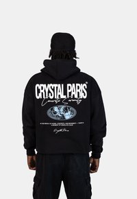 Czarna bluza z kapturem z dużym białym napisem "CRYSTAL PARIS" i wzorem globusu na plecach. Posiada kaptur ze sznurkiem i luźny krój.