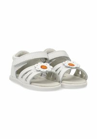 Sandalias blancas con múltiples correas cortadas, cierres de velcro ajustables y un acento de flor con un centro naranja en la parte delantera.