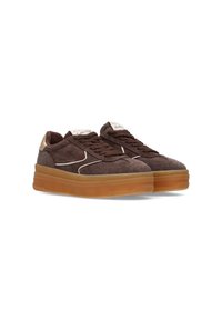 Bruine suède sneakers met een dikke tan rubberen zool, witte stiksels en beige accenten bij de hak. Vetersluiting met merknaam op de tong.
