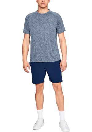 Men's athletic outfit: heathered dark blue short-sleeve top, navy shorts, white socks, and white sneakers. Casual, functional design.