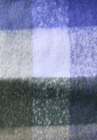 Uldtæppe med et ternet mønster i nuancer af lilla, beige og grøn med en blød, tekstureret finish.