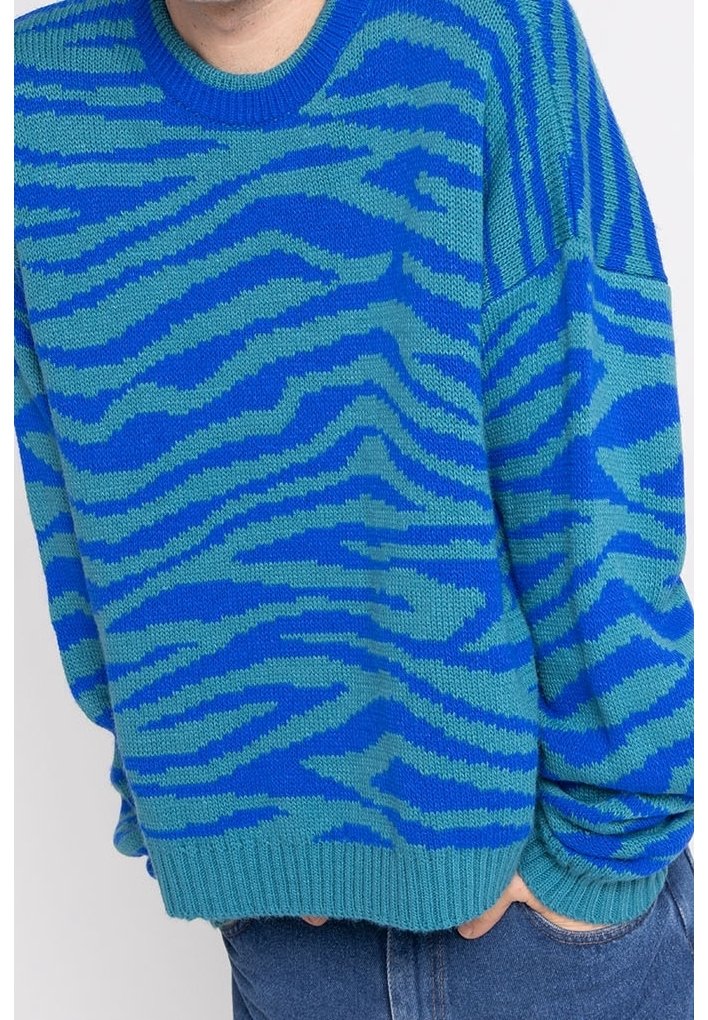 Blå stickad tröja med ett djärvt turkosa zebramönster, med rundad hals och ribbade ärmslut och nederkant. Mjuk textur.