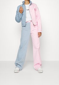 Džínová bunda s designem v barvách světle modré a růžové v blokovém stylu, doplněná růžovými a modrými širokými džíny. Oba kousky mají volný střih.