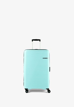 Valigia rigida colore azzurro chiaro con scanalature orizzontali, manico retrattile e quattro ruote nere girevoli su sfondo bianco.