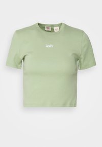 Beskurad grön bomullströja med korta ärmar, rund halsringning och vitt broderat "levi's"-logotyp på bröstet. Slät textur.