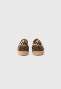 Chaussures en daim marron avec un talon en tissu imprimé léopard et une semelle en caoutchouc beige, présentant un design profil bas et une forme arrondie.