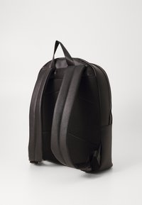 Zaino sintetico nero con superficie liscia, spallacci imbottiti e schienale in rete per la ventilazione. Design compatto con maniglia superiore.