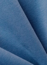 Lys blått stoff med en glatt tekstur, som viser et fint vevemønster. Materialet er drapert, og viser milde folder og lette skygger.