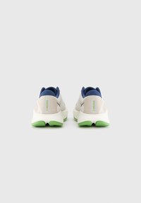 Chaussures de course avec une tige en mesh beige, des accents bleu marine, et une semelle extérieure verte. Elles disposent d'une semelle rembourrée et d'un design ventilé pour la respirabilité.